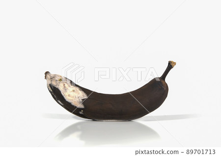 Spoiled banana on a white background with hard shadows and reflection. Organic waste overripe fruit. Ugly foods, fruits. Copy space 89701713