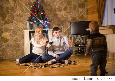Young family sitting in cozy house. Parents calling for their little boy Young family sitting in cozy house. Parents calling for their little boy 89704862