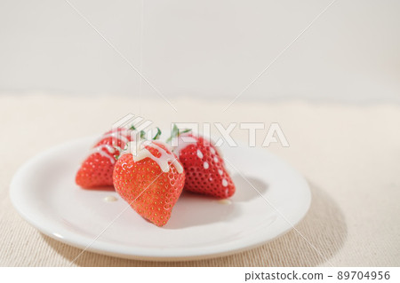 Condensed milk strawberries on a white plate 89704956