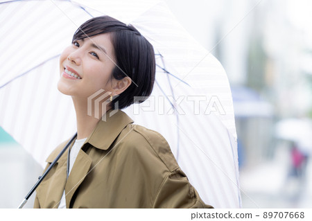 A woman walking with an umbrella 89707668