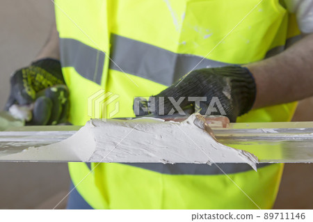 The master's hand holds a spatula with plaster, close. The master's hand holds a spatula with plaster, close. 89711146