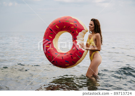 slender girl with a sexy body in a swimsuit with an inflatable circle in her hands is resting on the sea 89713724