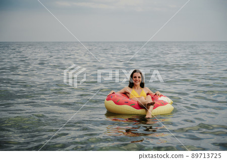 slender girl swims on an inflatable circle in the sea in summer 89713725
