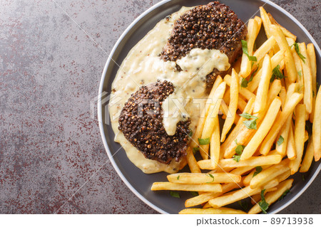 Roasted Steak Au Poivre and rich Cognac sauce served with french fries close-up in a plate. Horizontal top view Roasted Steak Au Poivre and rich Cognac sauce served with french fries close-up in a plate. Horizontal top view 89713938