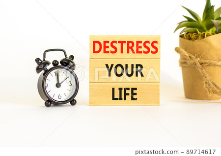 Destress your life symbol. Concept words Destress your life on wooden blocks. Black alarm clock. Beautiful white table white background. Psychological business destress your life concept. Copy space. 89714617