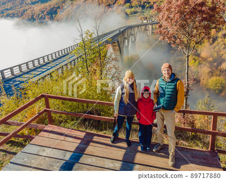 Montenegro. Happy family on the background of Dzhurdzhevich Bridge Over The River Tara foggy morning 89717880