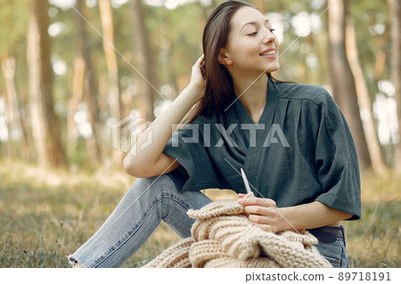 Girl in a park. Woman knitting outside. Lady working. 89718191