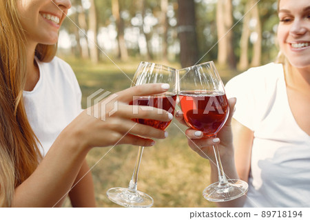 Beautiful girls on a picnic. Women in a spring forest. Ladies drinking a vine. 89718194