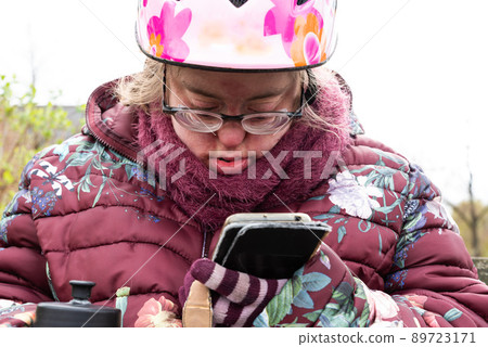 Close up outdoor portrait of a 39 year old white woman with Down Syndrome, making a call Close up outdoor portrait of a 39 year old white woman with Down Syndrome, making a call 89723171