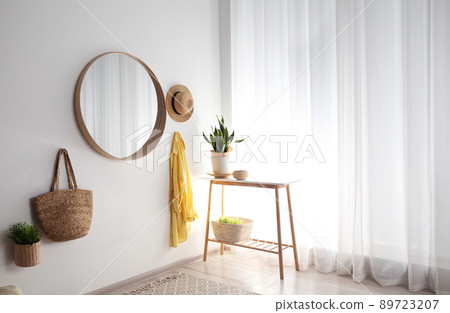 Round mirror with wooden frame on white wall in light room 89723207