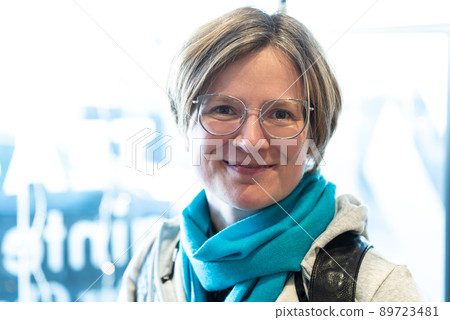 Indoor portrait of a smiling 35 year old white woman against a bokeh window 89723481