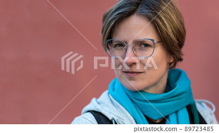 Portrait of a confident 35 year old white woman with a salmon pink colored background 89723485