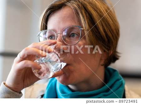Indoor portrait of a 35 year old woman drinking a glass of water 89723491