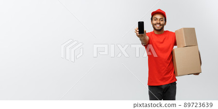 Delivery Concept - Portrait of Handsome African American delivery man or courier with box showing mobile phone on you to check the order. Isolated on Grey studio Background. Copy Space. 89723639