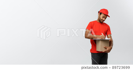 Delivery Concept - Portrait of Handsome African American delivery man or courier writing on a order document. Isolated on Grey studio Background. Copy Space. Delivery Concept - Portrait of Handsome African American delivery man or courier writing on a order document. Isolated on Grey studio Background. Copy Space. 89723699