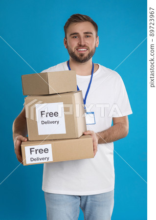 Male courier holding parcels with stickers Free Delivery on light blue background 89723967