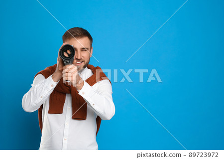Young man using vintage video camera on light blue background, space for text Young man using vintage video camera on light blue background, space for text 89723972