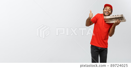 Delivery Concept - Portrait of Handsome African American Pizza delivery man showing thump up. Isolated on Grey studio Background. Copy Space. Delivery Concept - Portrait of Handsome African American Pizza delivery man showing thump up. Isolated on Grey studio Background. Copy Space. 89724025