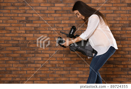 Operator with professional video camera near brick wall, space for text 89724355