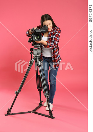 Operator with professional video camera on pink background Operator with professional video camera on pink background 89724371