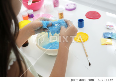 Little girl making DIY slime toy at table, closeup 89724436
