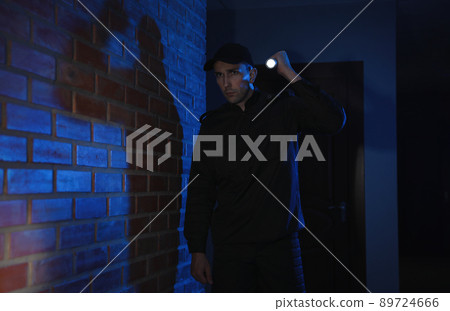 Male security guard with flashlight in dark corridor Male security guard with flashlight in dark corridor 89724666