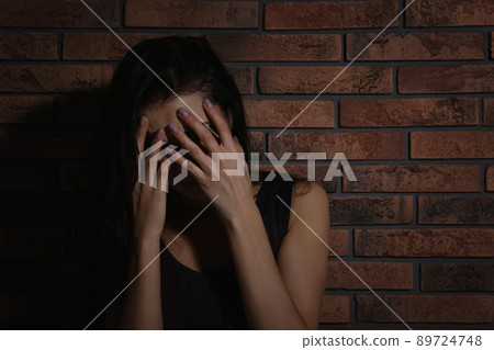 Crying young woman near brick wall. Domestic violence concept 89724748
