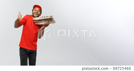 Delivery Concept - Portrait of Handsome African American Pizza delivery man showing thump up. Isolated on Grey studio Background. Copy Space. Delivery Concept - Portrait of Handsome African American Pizza delivery man showing thump up. Isolated on Grey studio Background. Copy Space. 89725468