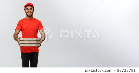 Delivery Concept - Portrait of Handsome African American Pizza delivery man. Isolated on Grey studio Background. Copy Space. 89725791