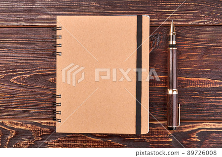 Notepad and pen on brown wooden desk. 89726008