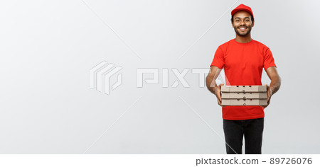 Delivery Concept - Portrait of Handsome African American Pizza delivery man. Isolated on Grey studio Background. Copy Space. 89726076