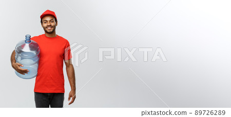Delivery Concept - Handsome African American delivery man holding water tank. Isolated on Grey studio Background. Copy Space. 89726289