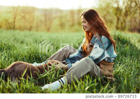 Woman happily smiling at playing with her little dog outdoors on fresh green grass in the summer sunshine her and her dog's health, Health Concept and timely treatment for insects ticks and tick fleas Woman happily smiling at playing with her little dog outdoors on fresh green grass in the summer sunshine her and her dog's health, Health Concept and timely treatment for insects ticks and tick fleas 89726713