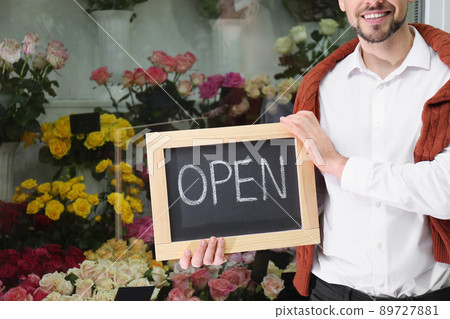 Male business owner holding OPEN sign in his flower shop, closeup 89727881