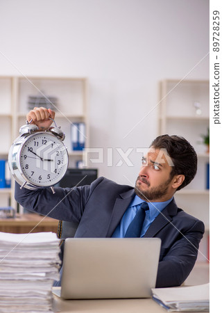 Young male employee in time management concept Young male employee in time management concept 89728259