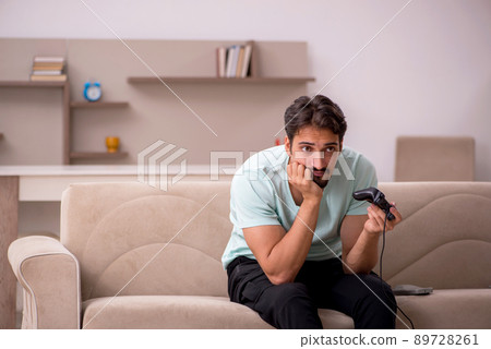 Young man playing joystick games at home Young man playing joystick games at home 89728261
