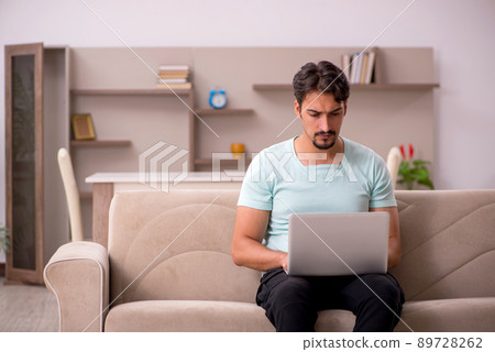 Young man sitting on the sofa with computer at home Young man sitting on the sofa with computer at home 89728262