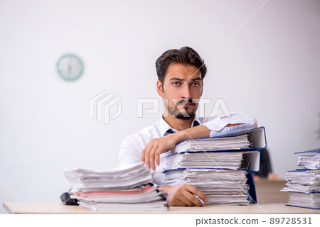 Young male employee and too much work in the office Young male employee and too much work in the office 89728531