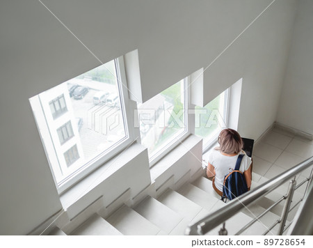 Thoughtful student is working with laptop on stairs at university campus. Woman uses wireless technologies for education. Homework online. Using Internet to search for information. 89728654