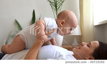 Authentic Young Caucasian Woman Holding Newborn Baby. Mom And Child On Bed. Close-up Portrait of Smiling Family With Infant On Hands. Happy Marriage Couple On Background. Childhood, Parenthood Concept Authentic Young Caucasian Woman Holding Newborn Baby. Mom And Child On Bed. Close-up Portrait of Smiling Family With Infant On Hands. Happy Marriage Couple On Background. Childhood, Parenthood Concept 89729260