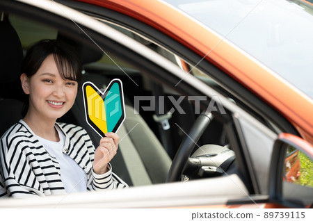 A smiling young woman with a beginner mark in the driver's seat A smiling young woman with a beginner mark in the driver's seat 89739115