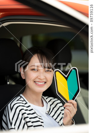 A smiling young woman with a beginner mark in the driver's seat A smiling young woman with a beginner mark in the driver's seat 89739116