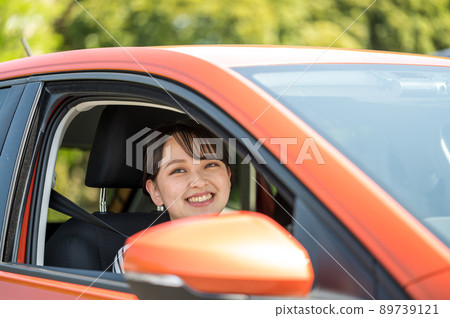A smiling young woman coming out of the window of a driving car A smiling young woman coming out of the window of a driving car 89739121