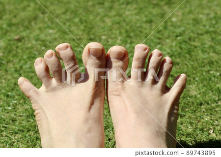 Bare feet with both toes spread out on the grass Bare feet with both toes spread out on the grass 89743895