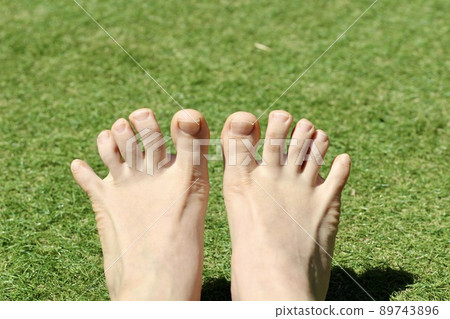 Bare feet with both toes spread out on the grass 89743896