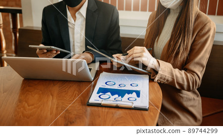 business documents on office table with tablet, smart phone and laptop and two colleagues discussing data in morning light. business documents on office table with tablet, smart phone and laptop and two colleagues discussing data in morning light. 89744299