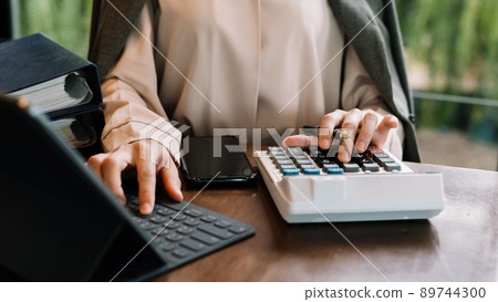 businessman working on desk office with using a calculator to calculate the numbers, finance accounting concept. 89744300