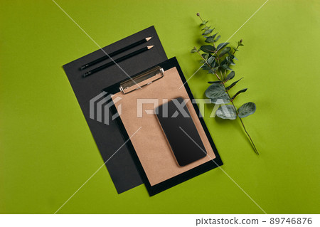 Top view in focus with different office equipment, supplies, stationery. Green background with copy space. Education, workplace concept. Close-up. 89746876
