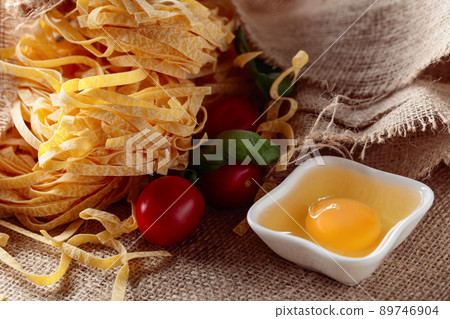 Homemade raw egg noodles with tomato and basil. 89746904