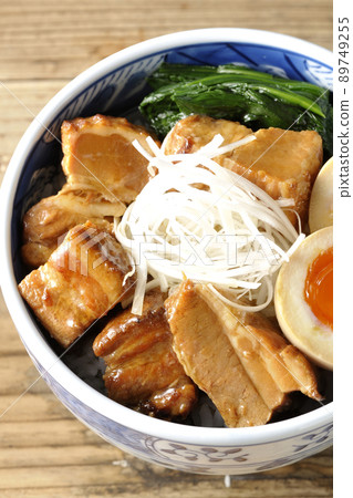 A bird's-eye view of a pork kakuni bowl with a soft-boiled egg, spinach, and white onions. 89749255
